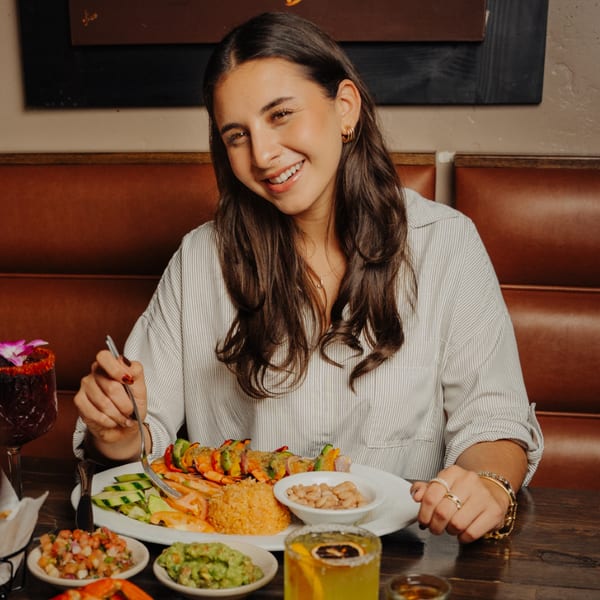 Smiling woman enjoying shrimp skewers, rice, beans, guacamole, and salsa at El Tarasco Restaurant.