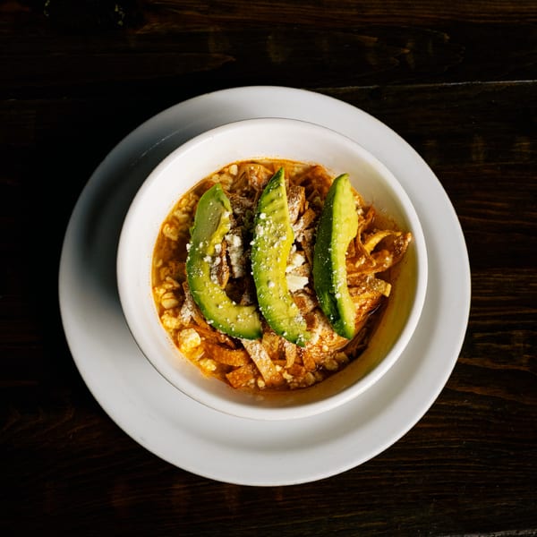 El Tarasco Restaurant Mooney's tortilla soup with avocado slices and crumbled cheese in a white bowl.