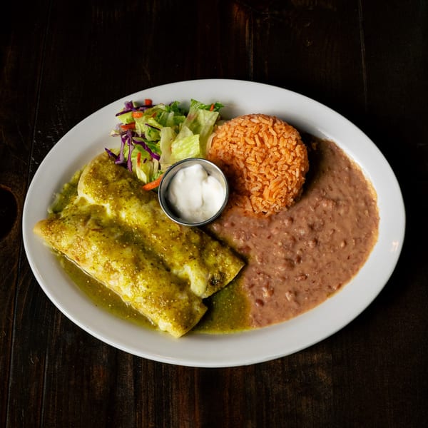 Two green enchiladas with rice, refried beans, a side salad, and sour cream.