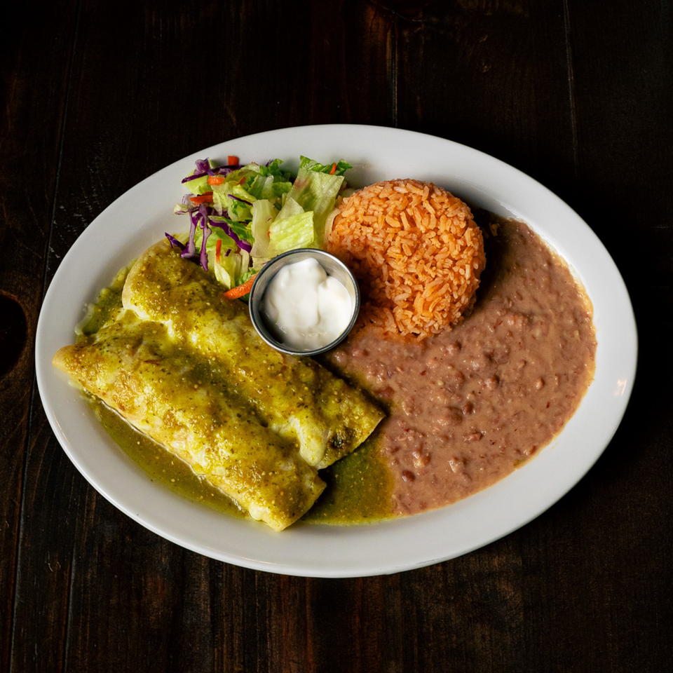 Two green enchiladas with rice, refried beans, a side salad, and sour cream.