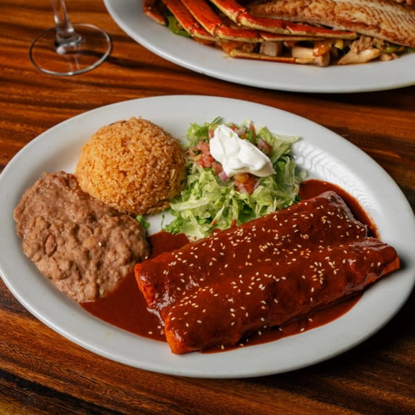 El Tarasco's enchiladas with mole sauce, sesame seeds, rice, refried beans, and salad with sour cream.