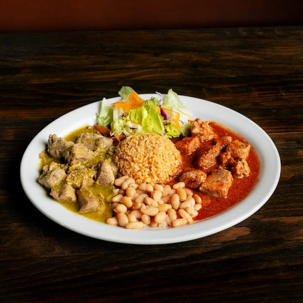A plate of Mexican food with green chile pork, red chile pork, rice, beans, and salad.